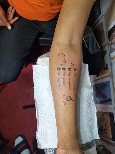 Fine-line script lettering tattoo on a forearm
